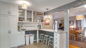 Eine Küche mit weißen Schränken, einer Granit-Arbeitsplatte und einem Essbereich mit Holztisch und Stühlen.