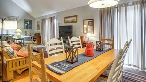 Ein Essbereich mit Holztisch, Stühlen, Fernseher und einer Couch.