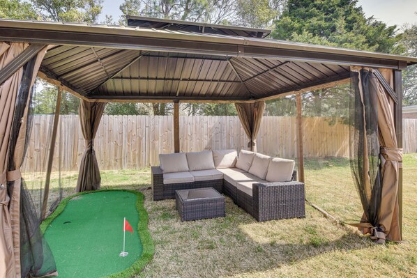 A covered patio area with a sectional sofa and a small table. - Golf, Ride & More! Home in Dtwn Southern Pines (Southern Pines)