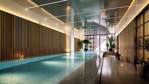 Ein Indoor-Pool mit modernem Design, mit einem langen, schmalen Becken, Holzverkleidung an einer Seite und einer Glaswand auf der anderen.