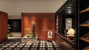 A lobby with a patterned floor, a reception desk, a plant display, and a decorative wall.
