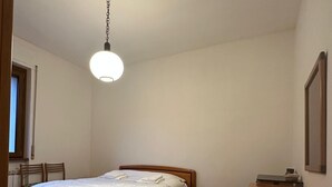 A bedroom with a bed, bedside tables, a dresser, and a hanging light fixture.