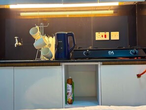 A kitchenette with a stove, a coffee maker, a hanging mug rack, and a bottle of dish soap. - Amazing studio in enchanting Nairobi for your stay (Nairobi)