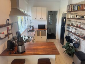 Uma cozinha moderna com ilha central, eletrodomésticos de aço inoxidável e diversos potes de armazenamento na parede.