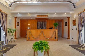 A reception area with a wooden desk, potted plants, and a marble floor. - Roman Base near Marco Simone (Roma)