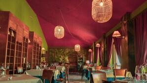 Un restaurant avec des tables dressées pour le service, un sol à carreaux et des lampes en osier suspendues au plafond.