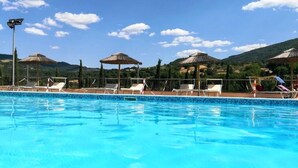 Une piscine entourée de collines, avec des chaises longues et des parasols.
