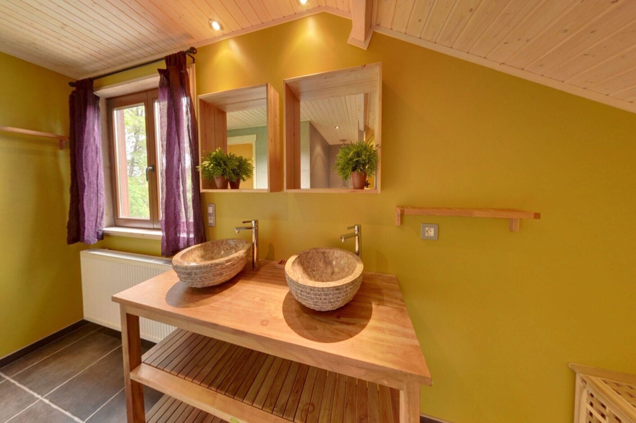 A bathroom with two stone sinks, wooden vanity, mirrors, and potted plants.