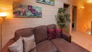 Ein Zimmer mit Holzvertäfelung, einem braunen Sofa, einem Blumentopf und zwei Wandgemälden.