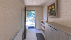 Ein Holzinterieur mit einer zur Außenseite führenden Tür, einem Bücherregal und einem gerahmten Gemälde.