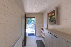 Ein Holzinterieur mit einer zur Außenseite führenden Tür, einem Bücherregal und einem gerahmten Gemälde.