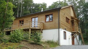 Eine Holzhütte mit Balkon, Treppe und einer Tür.