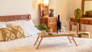 A neatly made bed with a decorative headboard, a bedside table with a wine bottle, a glass, and a small potted plant. - Villa Contessa, a peaceful sea-view retreat (Sardegna)