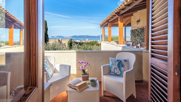 A balcony with wicker furniture, a book, and a potted orchid. - Villa Contessa, a peaceful sea-view retreat (Sardegna)