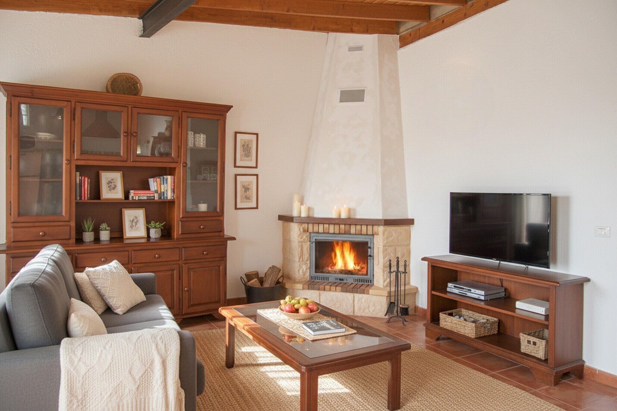 A living room with a fireplace, a sofa, a television, and a wooden cabinet.