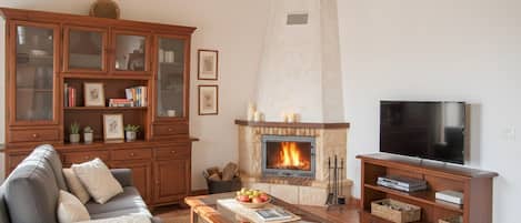 A living room with a fireplace, a sofa, a television, and a wooden cabinet.