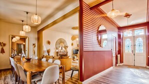 Un espace repas avec une table et des chaises en bois, un grand miroir et des luminaires suspendus.