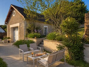Un bâtiment en pierre doté d’un balcon, d’un espace extérieur aménagé pour s’asseoir et d’un jardin.