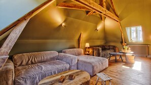 Une pièce de style « loft », avec un plafond en bois, un ensemble de canapés, une petite table et une lampe.