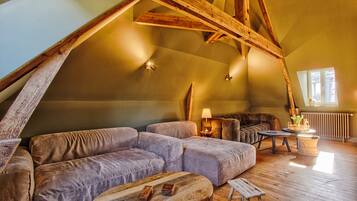 Une pièce de style « loft », avec un plafond en bois, un ensemble de canapés, une petite table et une lampe.