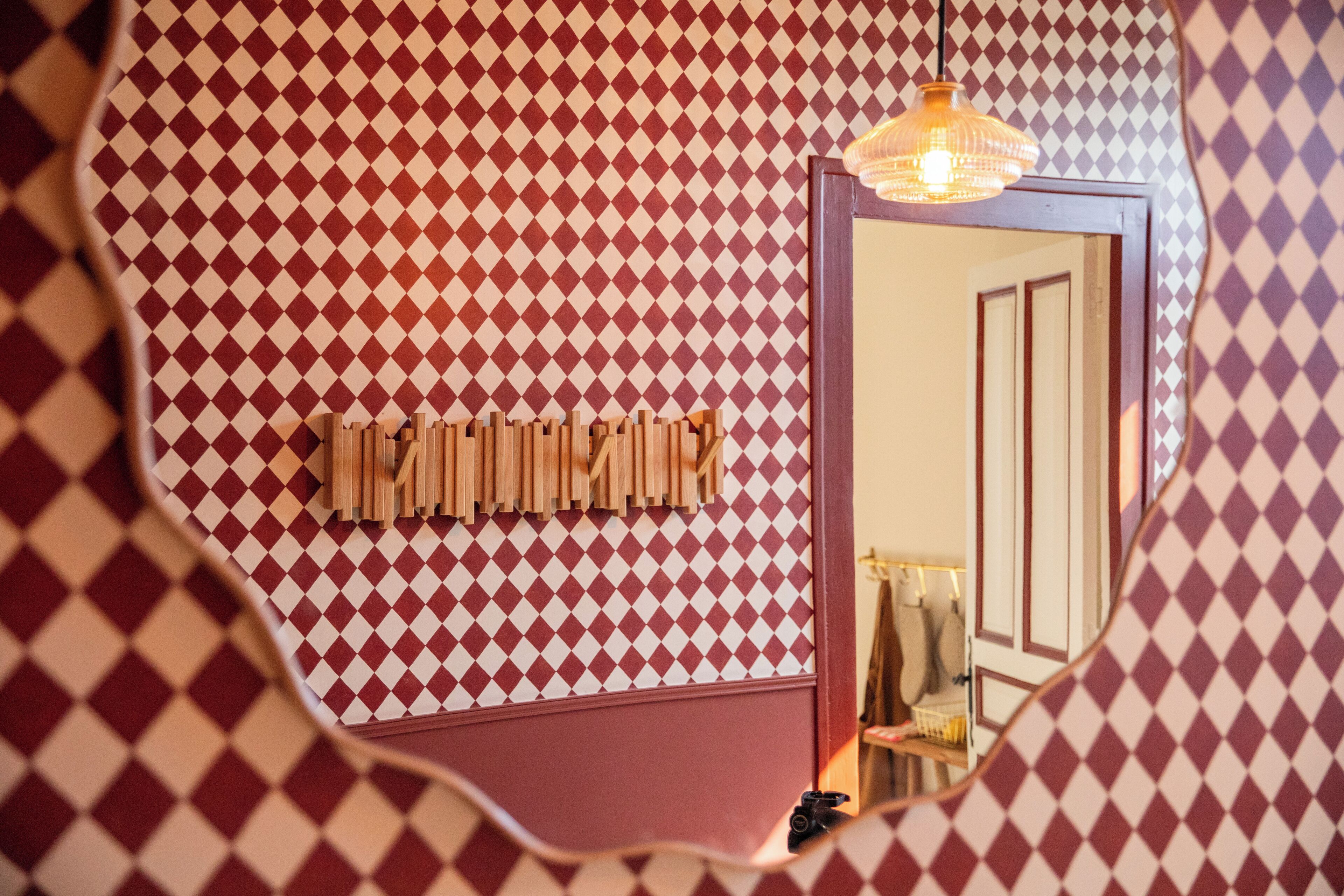 A room with a checkered wall pattern, a mirror, and a hanging light fixture.