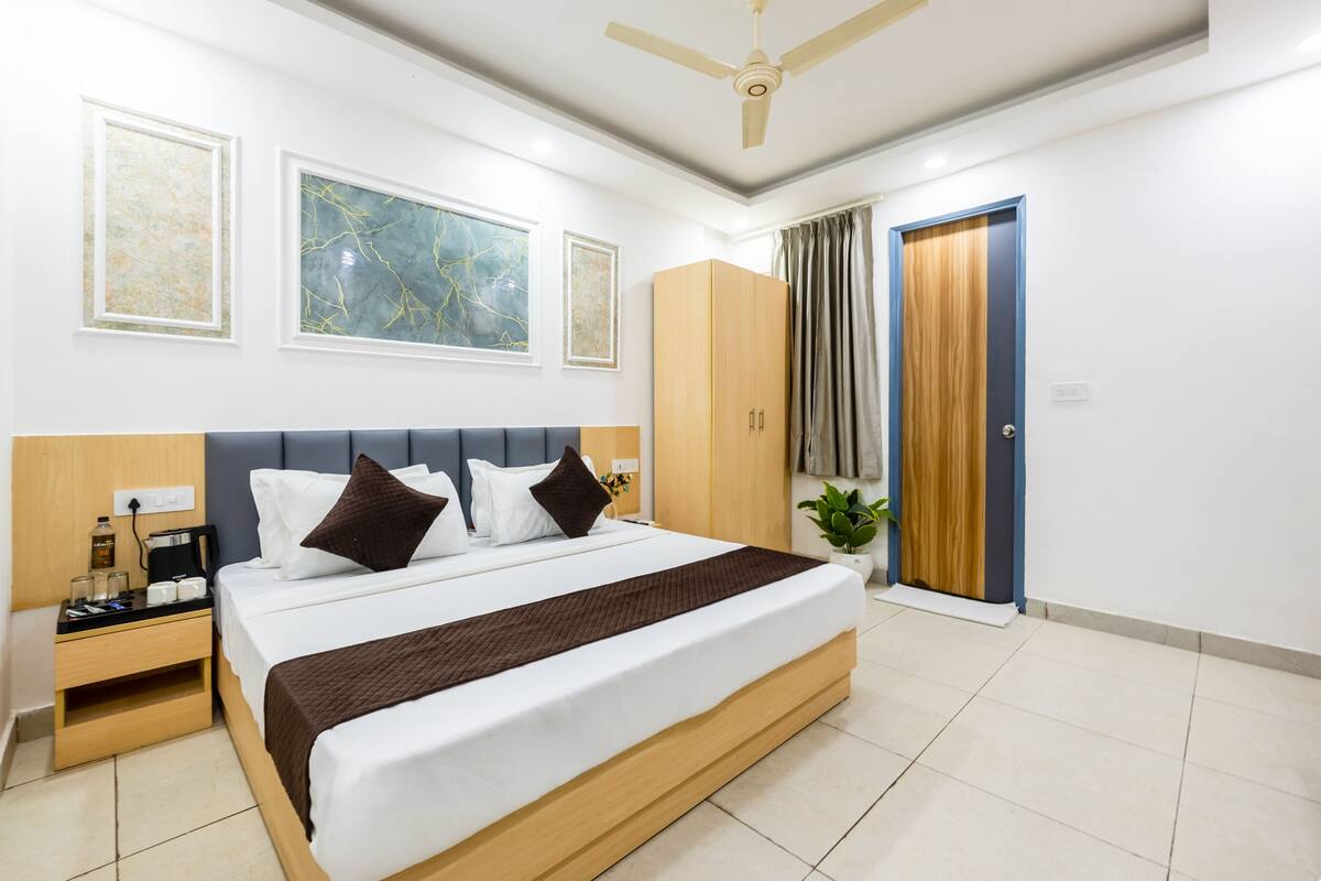 A hotel room with a large bed, a nightstand, a wardrobe, a ceiling fan, and framed artwork on the wall.