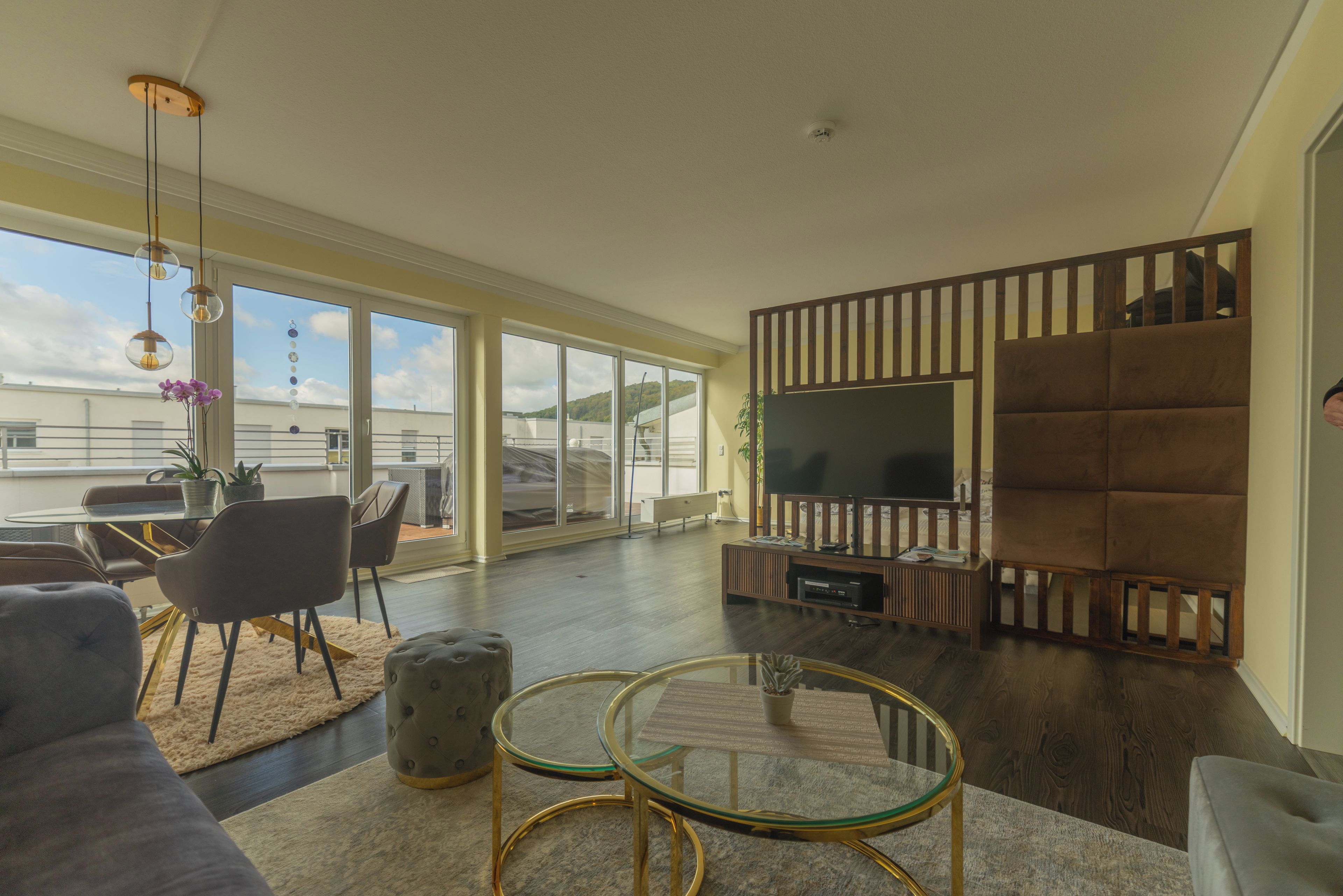 A modern living room with a large flat-screen TV, comfortable seating, and a glass coffee table.