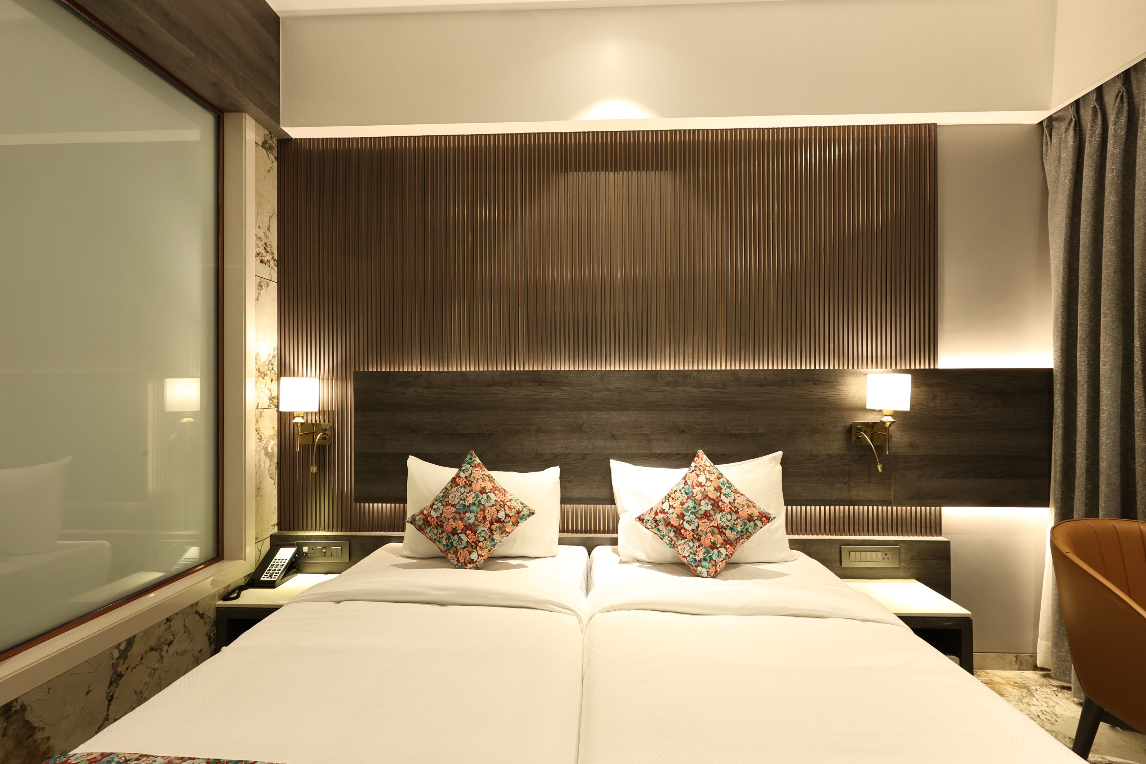 Une chambre d’hôtel avec un grand lit, deux tables de chevet, une commode, un miroir et une fenêtre.