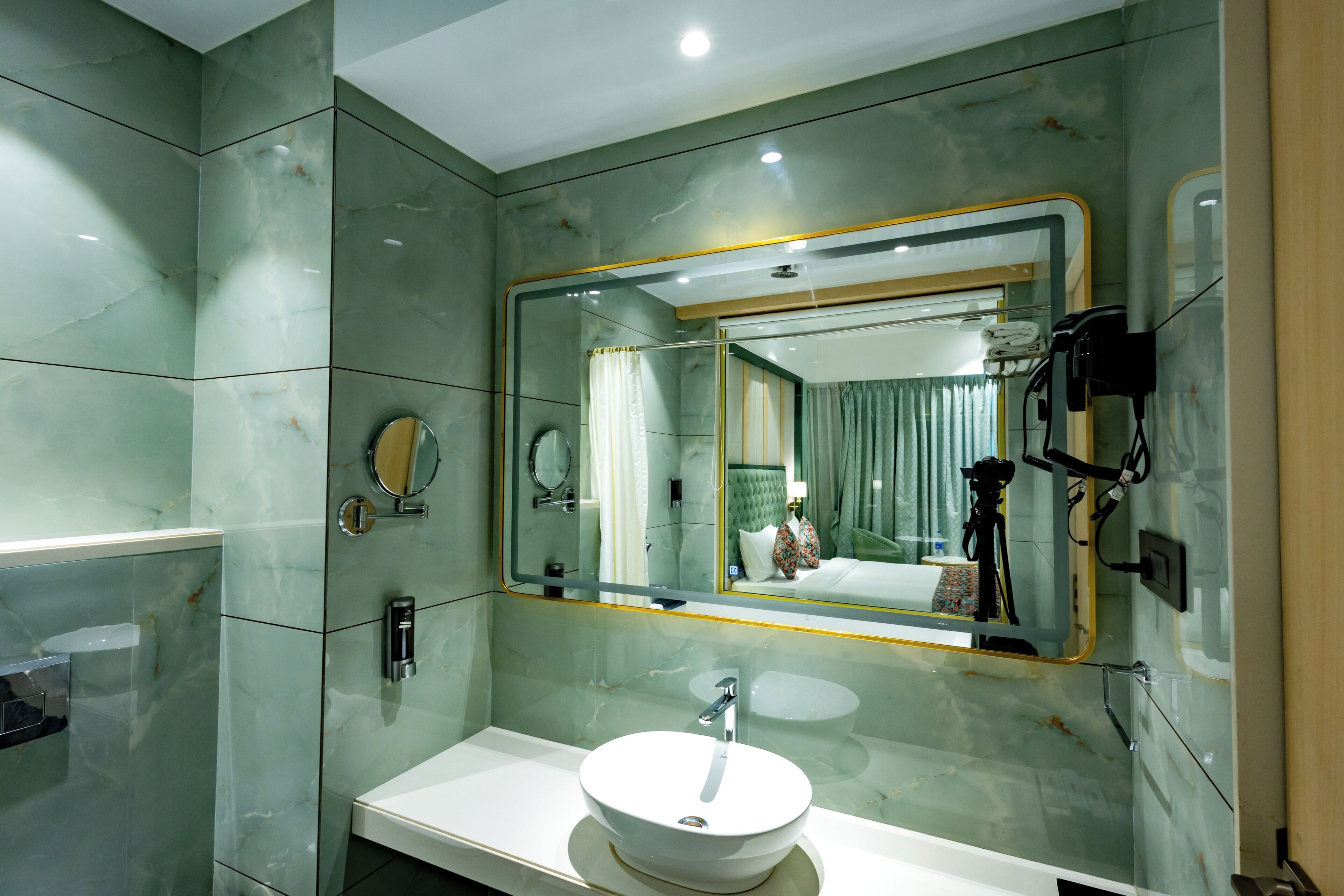 Un baño con un lavamanos blanco, un espejo grande y una zona de ducha.
