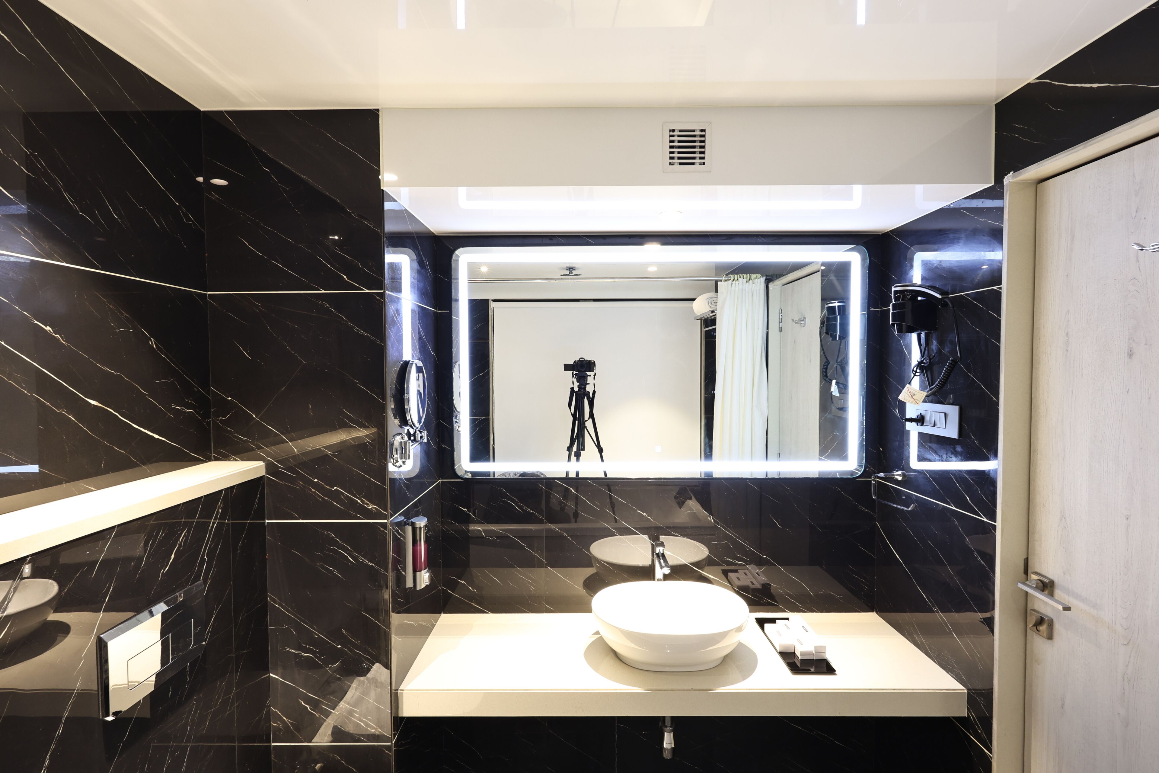 Un baño moderno con un espejo grande, un lavabo redondo y un tocador con espejo.