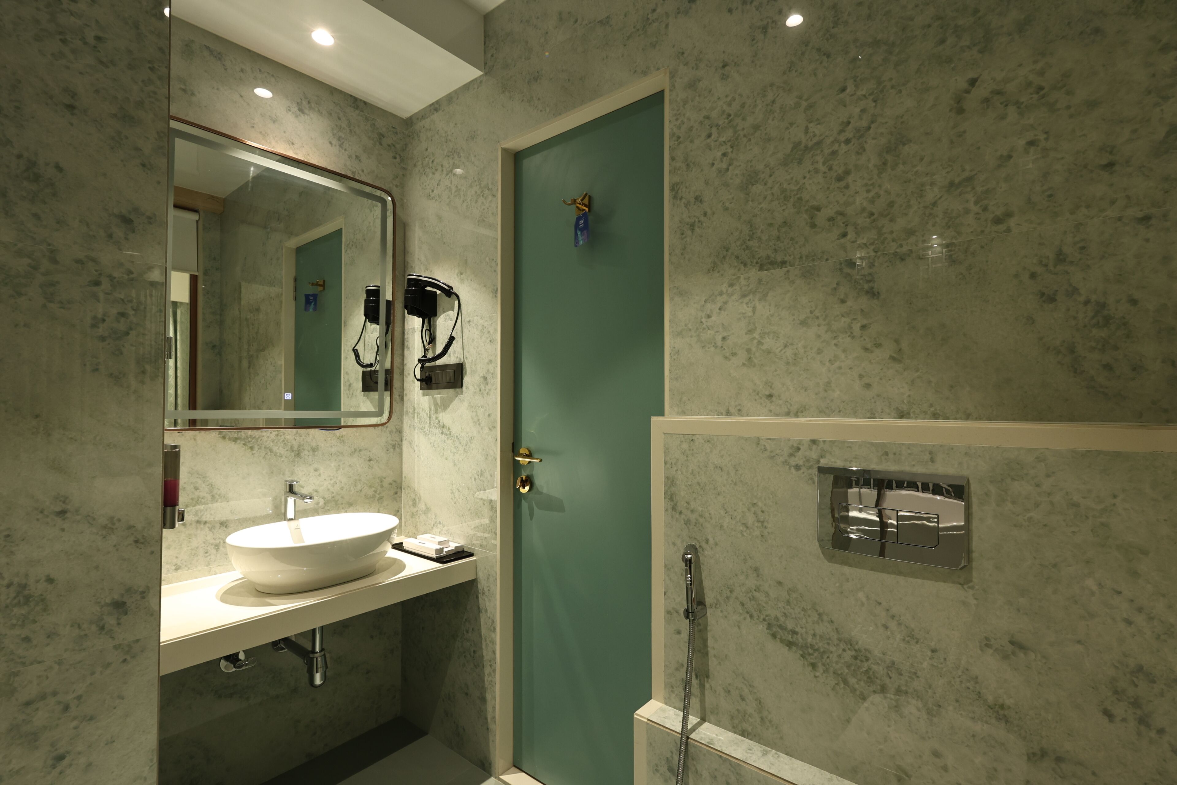 Ein Badezimmer mit weißem Waschbecken, einem Spiegel, einer grünen Tür und einer Dusche.