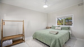 Ein Schlafzimmer mit einem Bett, einem Holzschrank, einem Fenster mit Blick und einem Deckenventilator.
