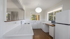 Eine moderne Küche mit weißen Schränken, einer Holz Arbeitsplatte, einem eingebauten Geschirrspüler und einem Fenster für natürliches Licht.