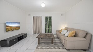 Sala de estar com televisão, sofá, mesa de centro e tapete estampado.