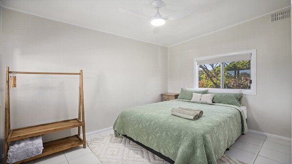 Ein Schlafzimmer mit einem Bett, einem Holzschrank, einem Fenster mit Blick und einem Deckenventilator.
