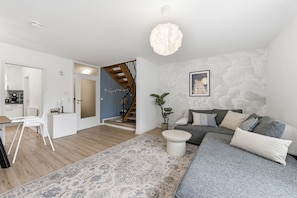 Ein modernes Wohnzimmer mit einem grauen Sofa, einem weißen Couchtisch und einem gemusterten Teppich.
