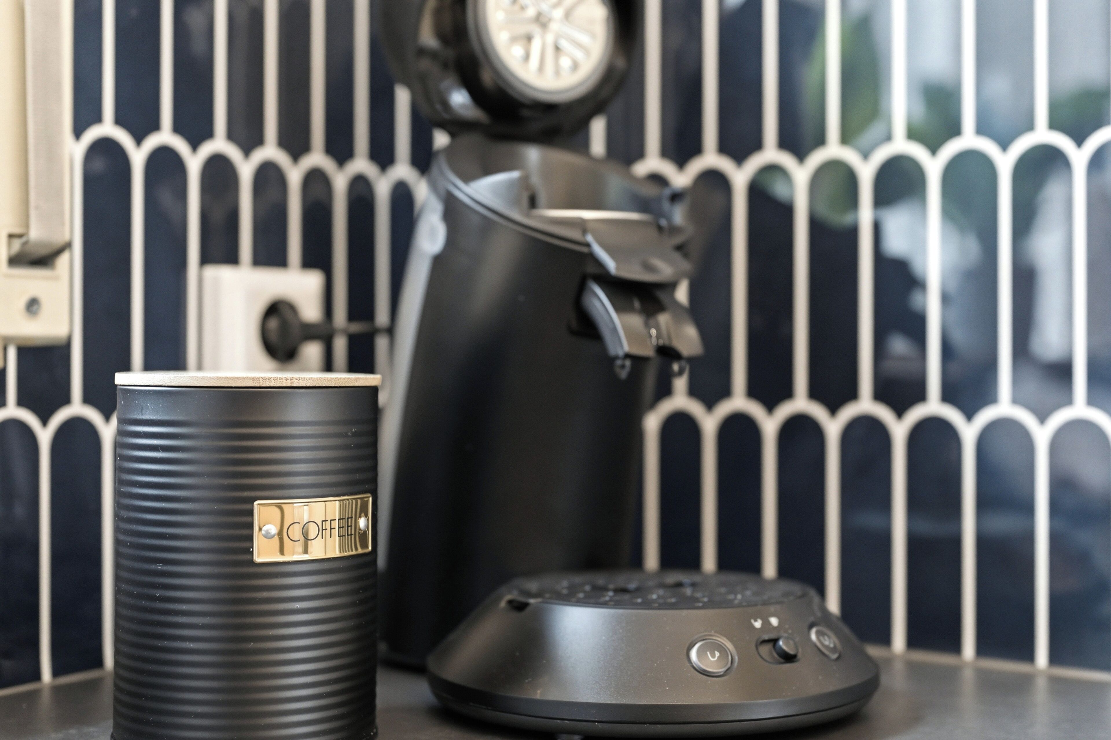 A coffee maker, a coffee pot, and a coffee pod dispenser on a countertop.