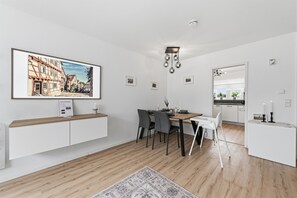 A modern dining area with a wooden table, chairs, and a large framed picture on the wall. - Stylish apartment in the center for 6 people + parking space (Bad Wimpfen)