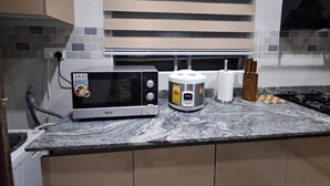 A kitchen with a microwave, a rice cooker, and a gas stove.