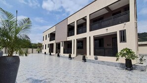 Een modern gebouw met meerdere balkons, een overdekt terras en potplanten.
