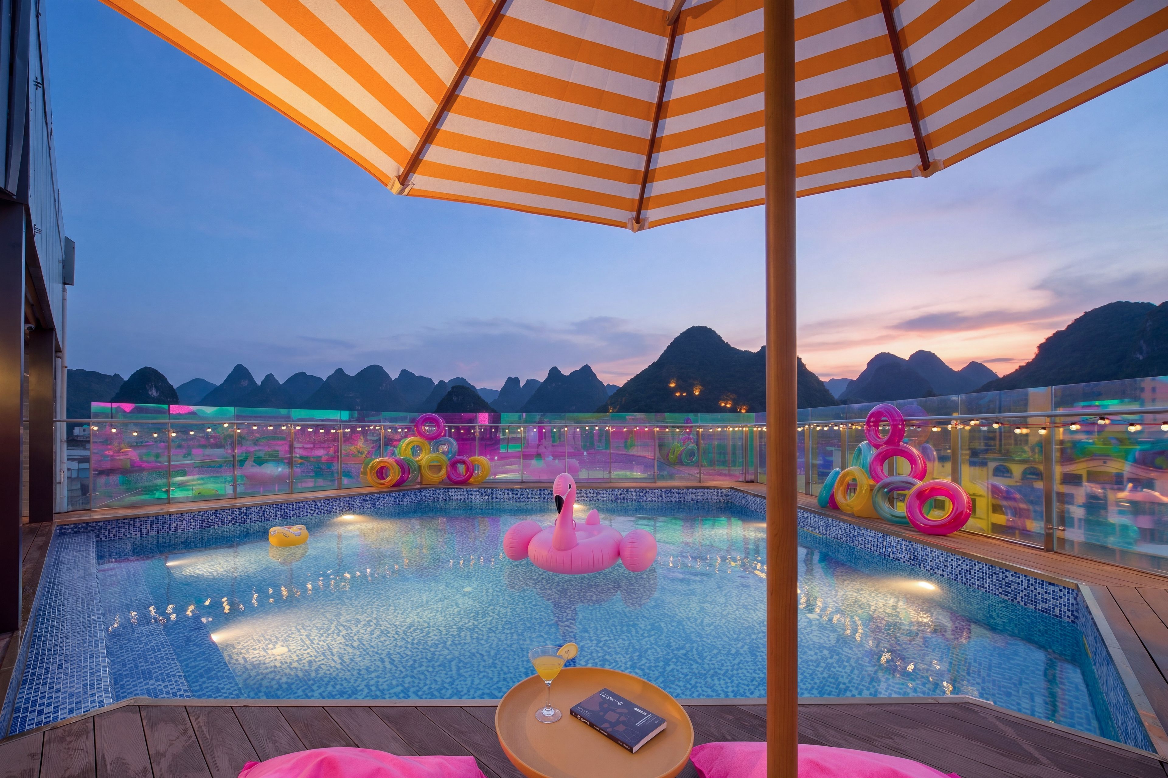 Un área de piscina con vistas a montañas, un flotador de flamenco y anillos de colores.