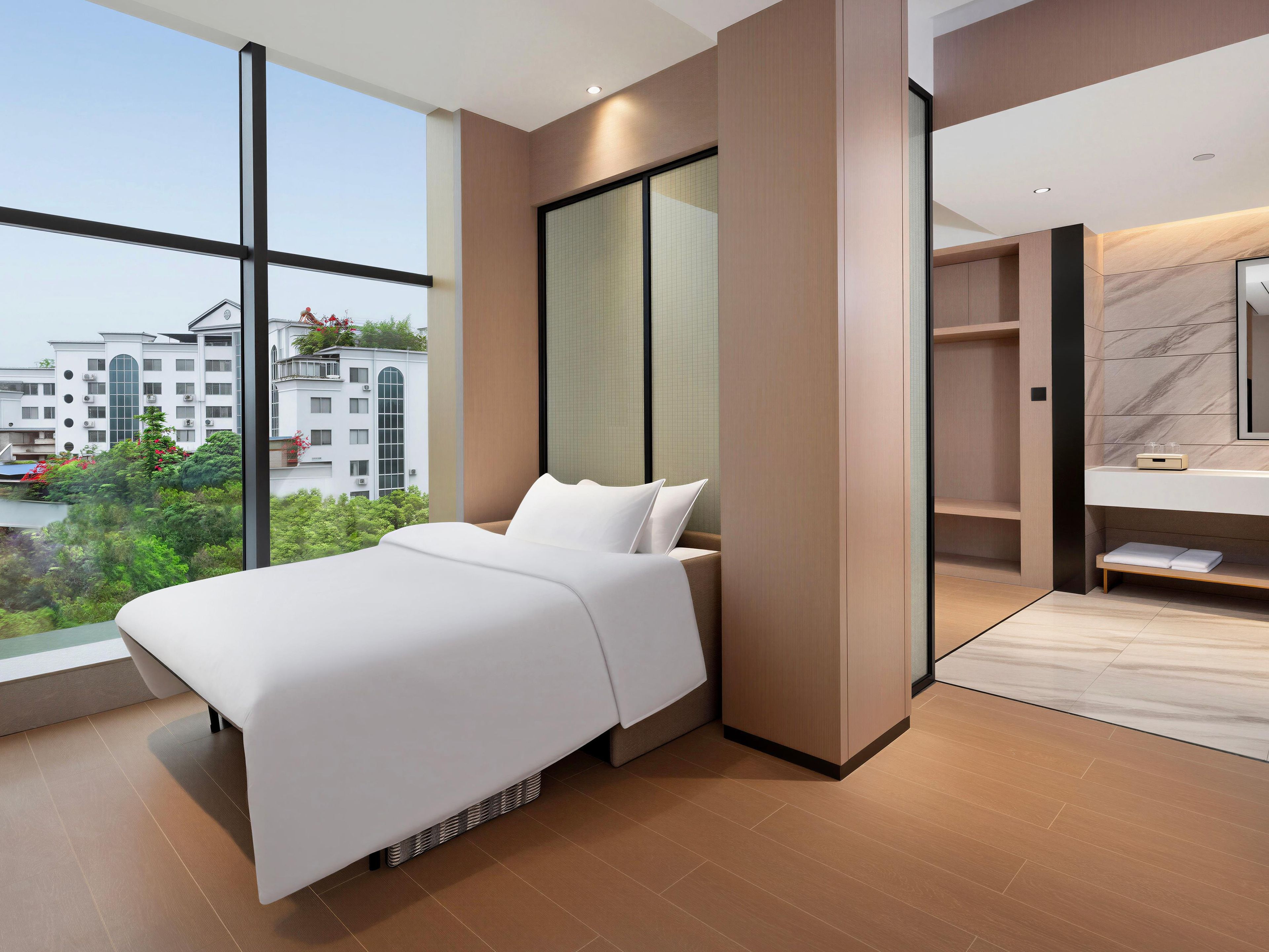 A modern hotel room with a large bed, a walk-in closet, and a bathroom with a marble countertop.