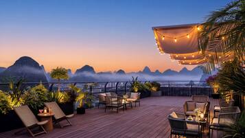 Une terrasse sur le toit avec des sièges en plein air, une vue sur le paysage urbain et un coucher de soleil.
