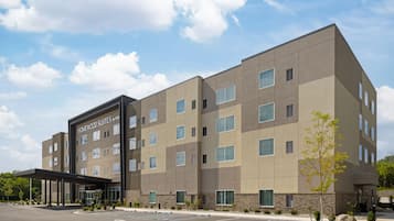 Ein mehrstöckiges Hotel mit modernem Design, das einen markanten Eingangsbereich und einen Parkplatz vor der Fassade hat.
