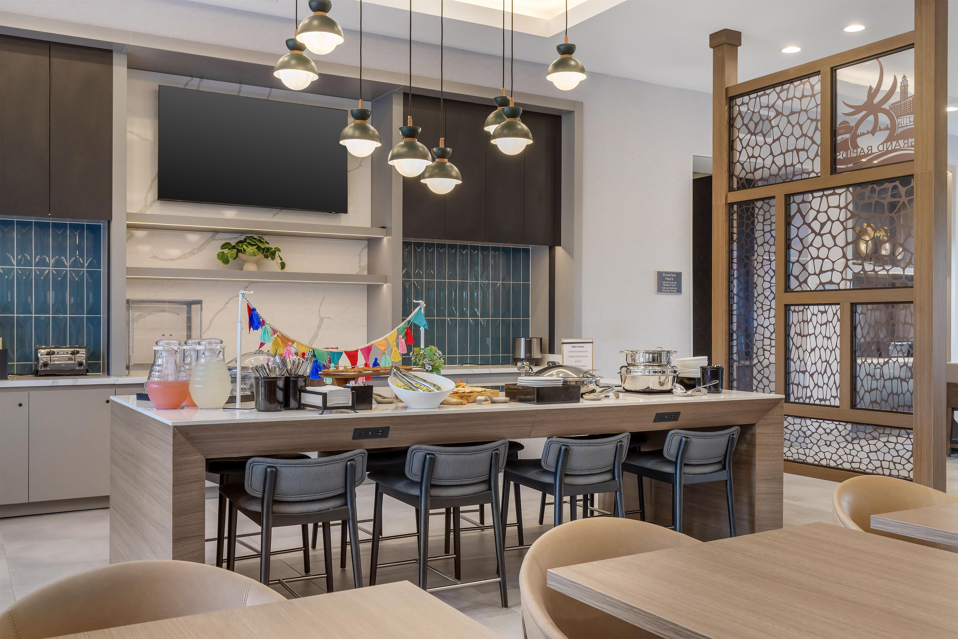 Una cocina moderna con una isla central, taburetes de bar e iluminación colgante.