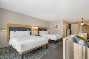 A hotel room with two beds, a sofa, a desk, and a wardrobe.