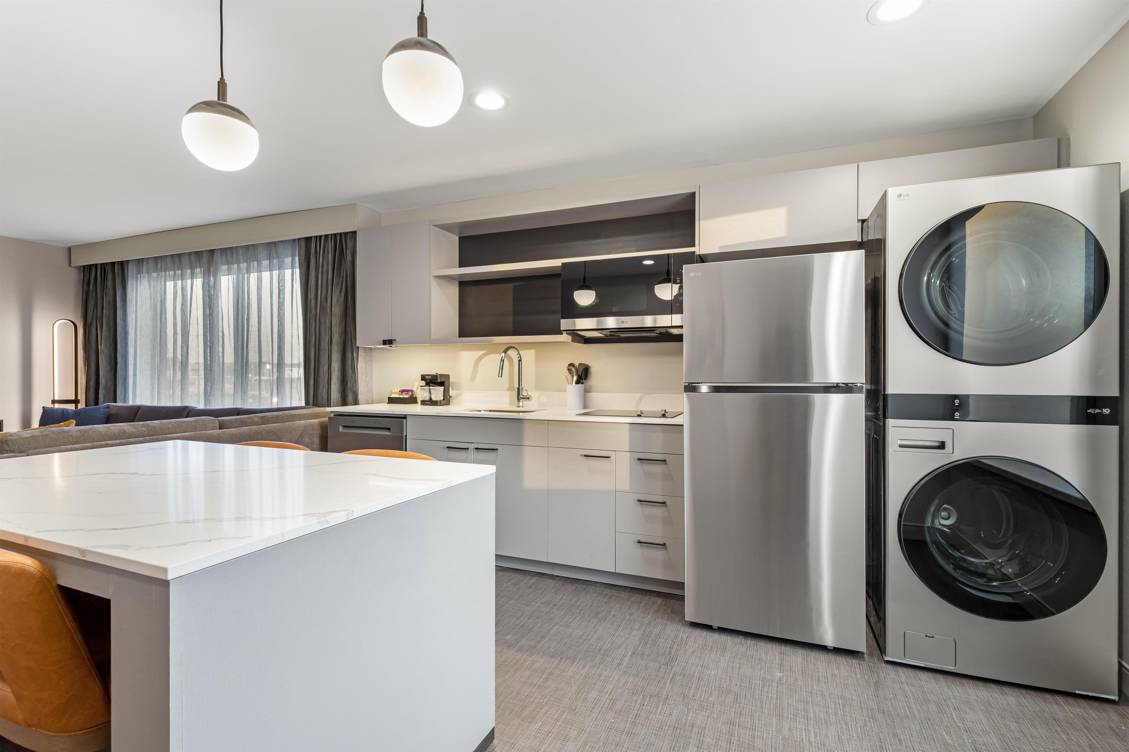 Una cocina moderna con una isla central, electrodomésticos de acero inoxidable y lavadora y secadora integradas.