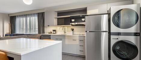 Una cocina moderna con una isla central, electrodomésticos de acero inoxidable y lavadora y secadora integradas.