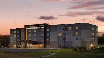 Een meerhoog hotel met een opvallend bord met de tekst 'Homewood Suites by Hilton'.