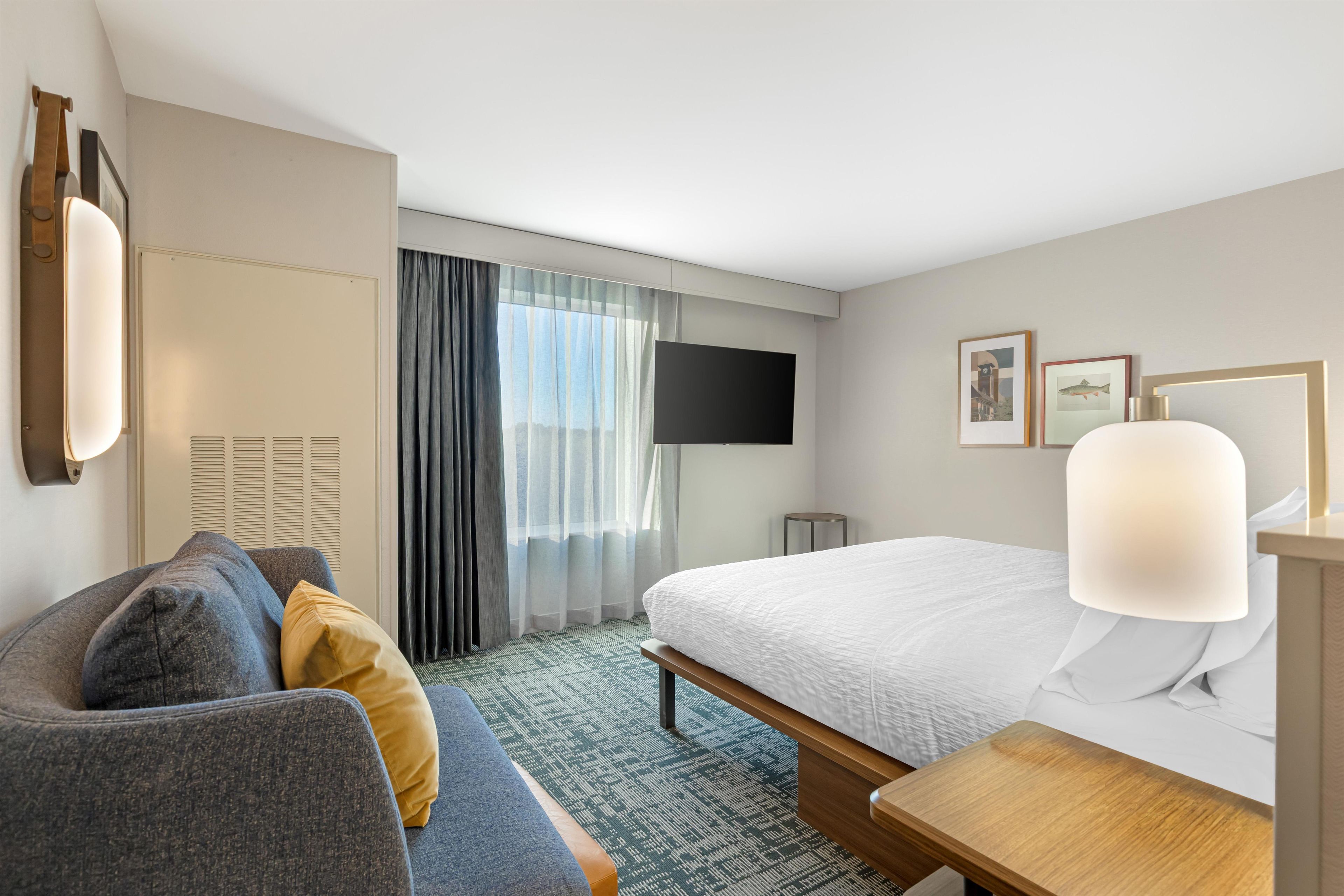 A hotel room with a bed, a sofa, a TV, and a desk.